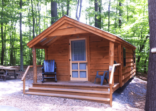 A 12x16 Home Office built with live edge pine siding and skinned hemlock porch posts. building was set up at a campground. 