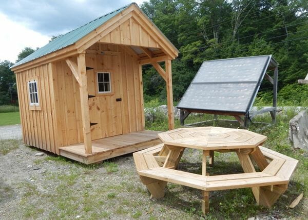 8x12 Nook post and beam cabin sitting next to an octagon picnic table and solar shed