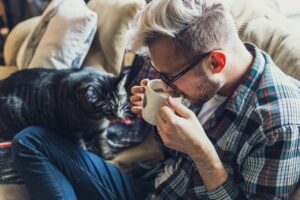 Alt tag: A man drinking coffee and a cat on his lap