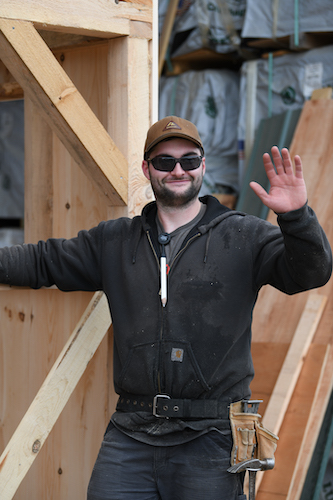 Carpenter Luke smiling and waving while constructing a Jamaica Cottage Shop Fully Assembled Building