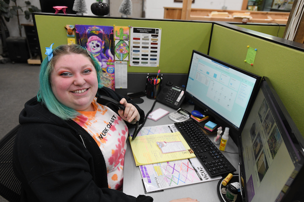 Hali smiles and holds a telephone while she works as Sales Associate in the JCS sales office
