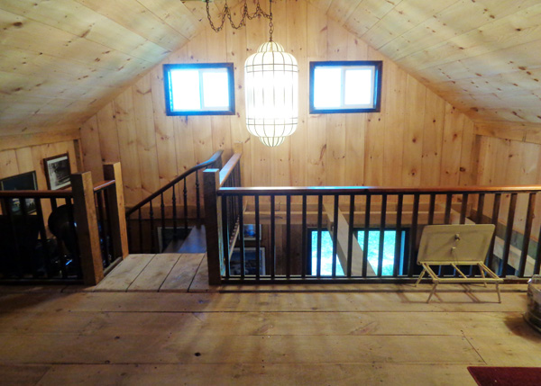 Custom built loft with railing in a 20x40 Vermont Cabin