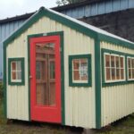 8x10 Greenhouse painted yellow with green trim and a red combo glass screen door