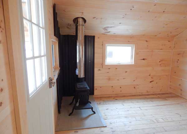 Small cabin with finished interior and a woodstove.