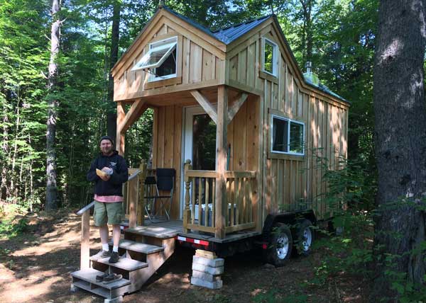 Tiny House on Wheels with a porch, built for off-grid living.
