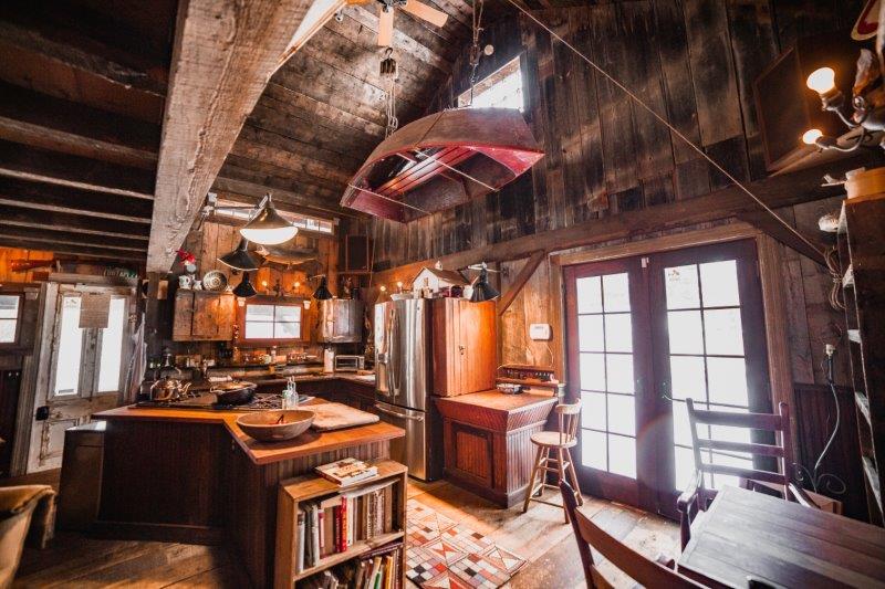 Rustic and charming cabin kitchen with hanging red upside down canoe, wooden countertops, and French doors to the outside.