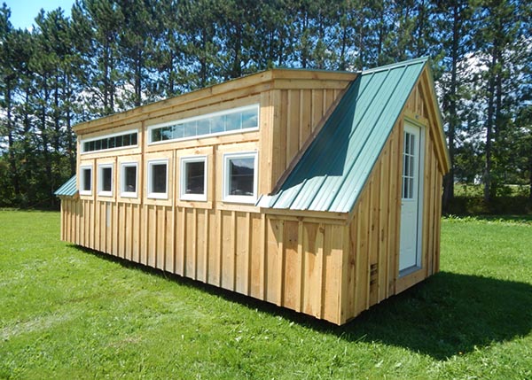 12x20 cabin with dormer with six insulated awning windows and two fixed transom windows, green metal roof, nine-lite door.