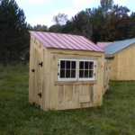 Tiny chicken coop with a red metal roof.