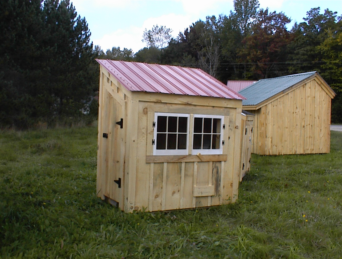 Tiny chicken coop with a red metal roof.