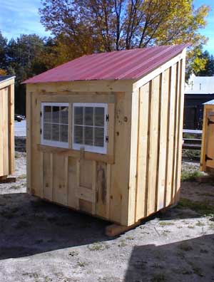Small chicken coop with a red metal roof and pine board and batten siding.