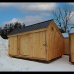 Post and beam storage shed with three sliding barn doors and a black metal roof
