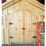 Arched double doors made from pine that are designed to fit in sheds and garages.