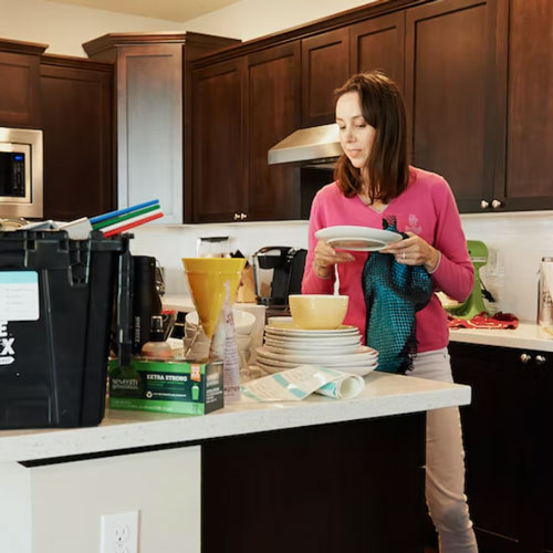 Woman placing her dishes on a countertop for spring cleaning
